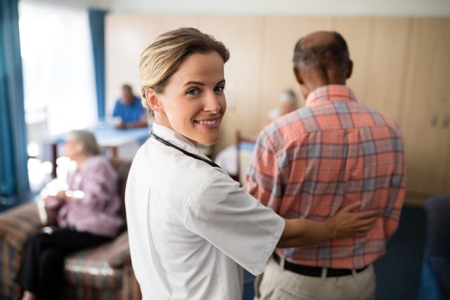 Smiling female doctor assisting a senior man in a retirement home. Ideal for use in healthcare, elderly care, and retirement home promotional materials. Highlights compassionate care and professional medical support for the elderly.