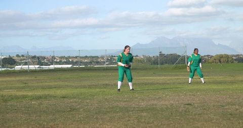 Female softball teammates on green field outdoors