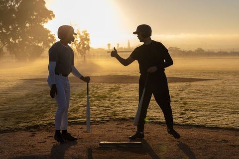 Sunrise baseball coaching: players giving thumbs-up at home plate in misty dawn