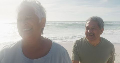 Senior Couple Strolling On Beach During Sunset