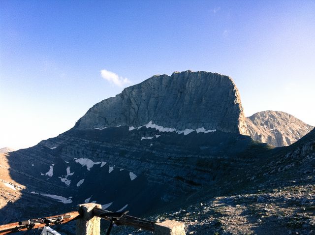 This image shows a majestic rocky mountain peak illuminated by early morning sunlight, under a clear blue sky. Ideal for promoting outdoor adventure activities such as hiking and climbing. Perfect for use in travel brochures, nature magazines, environmental publications, or outdoor gear advertisements.