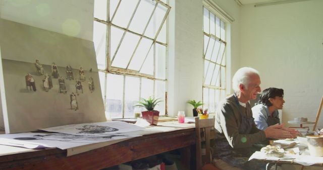 Artists focusing on their creations in a bright, sunlit studio. Can be used for illustrating creative process, art workshop environments, or artistic collaboration. Ideal for websites or articles related to art, creativity, and education.