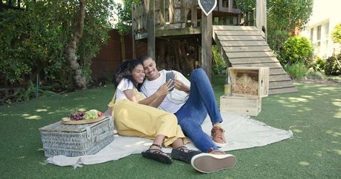 Diverse couple enjoying garden picnic and weekend leisure with technology