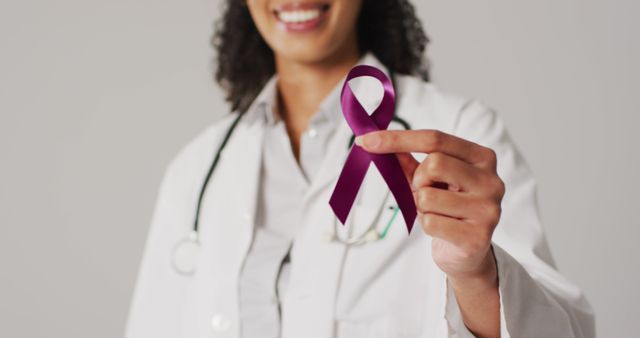 Image of smiling biracial female doctor holding purple pancreatic cancer ribbon - Download Free Stock Photos Pikwizard.com