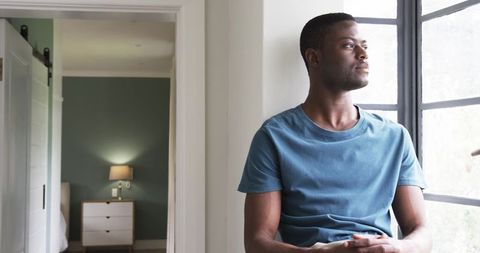 Man gazing outside window in cozy interior with natural light