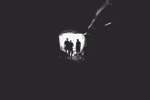 Silhouetted figures at tunnel exit into bright light
