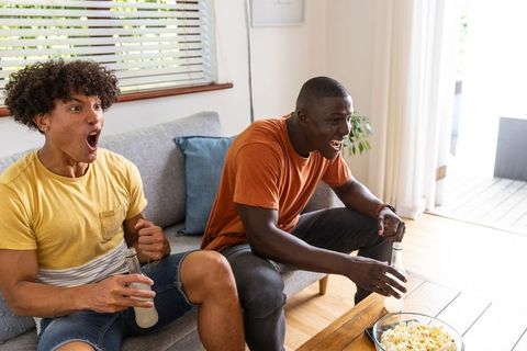 Two friends reacting with surprise while watching game at home