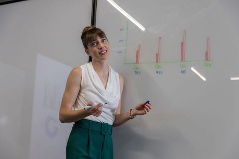 Business professional presenting data on whiteboard in modern meeting room