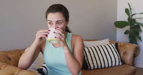 Relaxing Woman Sipping Coffee on Cozy Sofa
