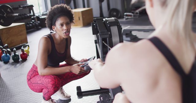 Image of diverse, happy female trainer encouraging woman on rowing machine working out at a gym - Download Free Stock Photos Pikwizard.com
