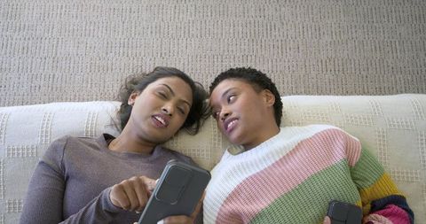 Diverse friends relaxing at home sharing smartphone content