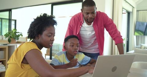 African American family collaborating on laptop at home helping child with homework