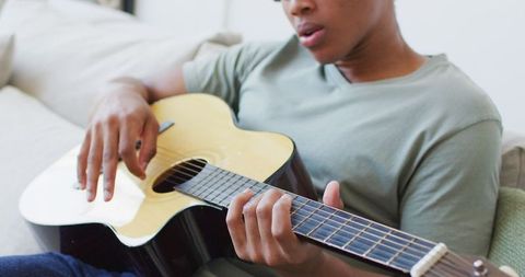 Man Relaxing While Playing Acoustic Guitar at Home