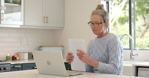 Senior Woman Working Remotely at Home in Modern Kitchen