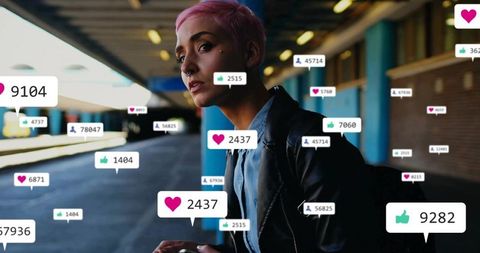 Young woman with pink hair checking social media likes on phone at train platform