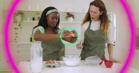 Cracking egg and whisking batter in bright kitchen, two women collaborating on baking