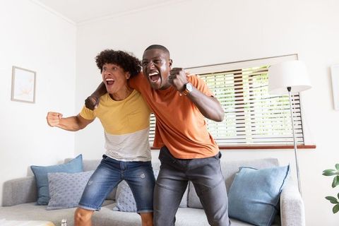 Diverse Friends Cheering in Living Room Scene with Natural Light