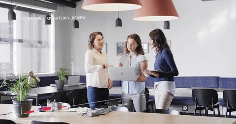 Three businesswomen collaborating over laptop reviewing fiscal charts in modern office