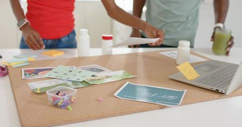 Collaborative corkboard planning with photos, prints and laptop for creative studio