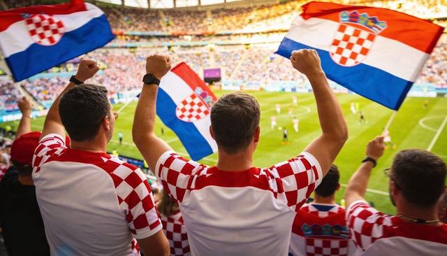 Cheering croatian football fans waving flags wearing red-and-white checkered jerseys