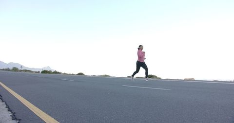 Woman running on open road with mountain landscape
