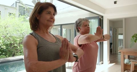 Mature Women Practicing Yoga with Smartwatches Near Pool for Wellness
