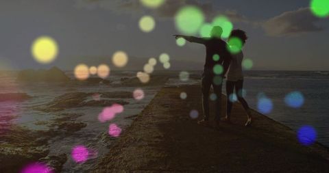 Couple Admiring Ocean Sunset with Colorful Bokeh Lighting