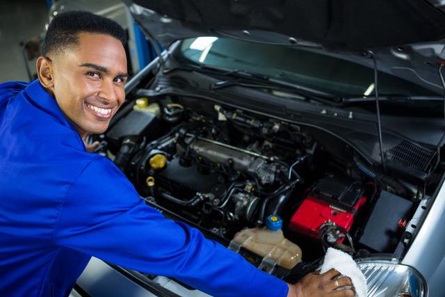Portrait of happy mechanic servicing car at repair garage