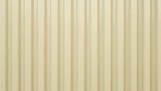 Beige corrugated metal wall featuring vertical ridges, dents and industrial texture