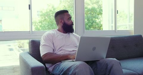 Man with Laptop Relaxing by Window in Modern Living Room