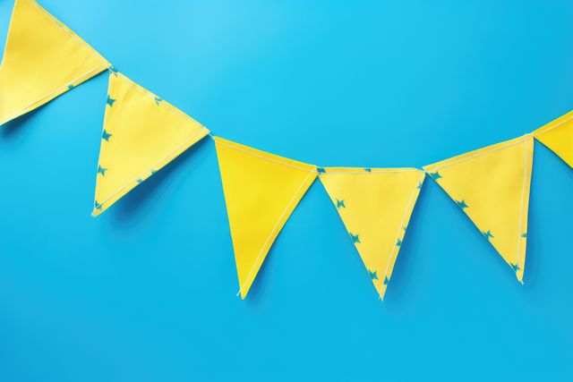 Bright yellow pennant flags arranged against a vivid blue background, creating a festive and cheerful atmosphere. Perfect for advertising party decorations, celebrating events, crafting materials, and bright color themes.