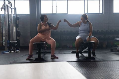 African american women exchanging fist bump in gym during supportive strength training