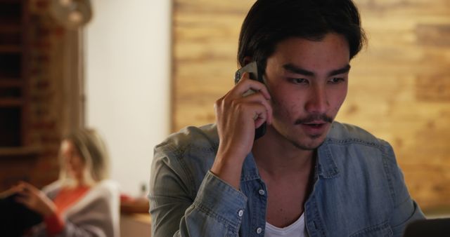 Focused Young Man Talking on Phone While Working from Home - Download Free Stock Images Pikwizard.com