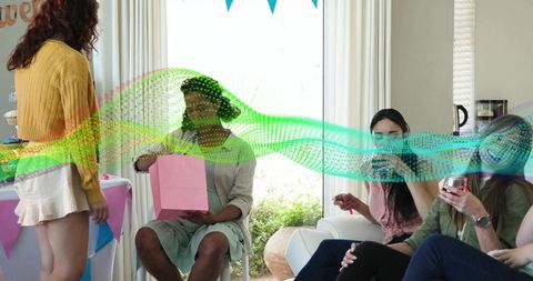 Friends opening gift at casual living room party with bunting, drinks and festive decor