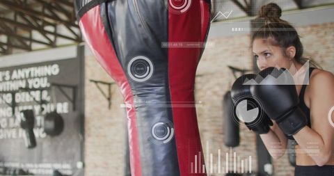 Female boxer training with digital hud overlay punching heavy bag in industrial gym