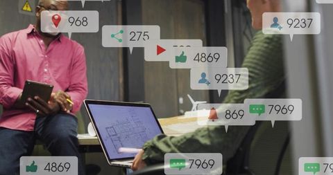 Collaborating over digital blueprint with social media notification overlays at modern desk