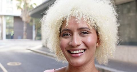 smiling young woman with curly blonde hair in urban cover theme - Download Free Stock Images Pikwizard.com