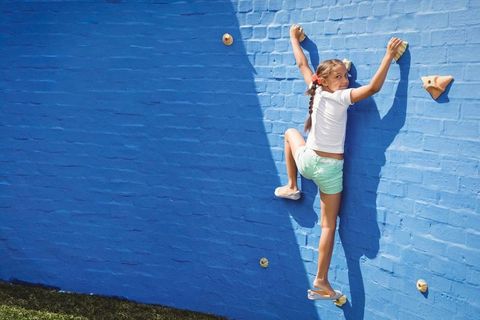 Young Girl Climbing Bright Blue Wall with Bold Handholds - Download Free Stock Images Pikwizard.com