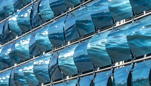 Reflecting curved blue panels creating rippling light pattern on architectural facade