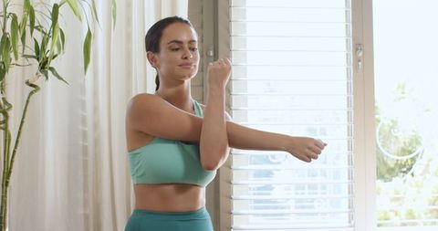 Woman doing arm stretch at home in modern fitness corner