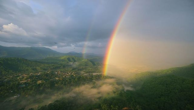 Stunning double rainbow arches over misty rural valley