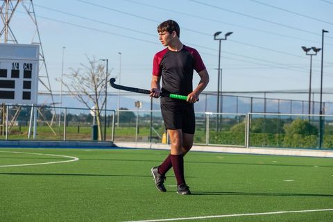 Teenage Field Hockey Player Holding Stick on Turf Court