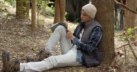 Man writing in notebook amidst tranquil forest surroundings