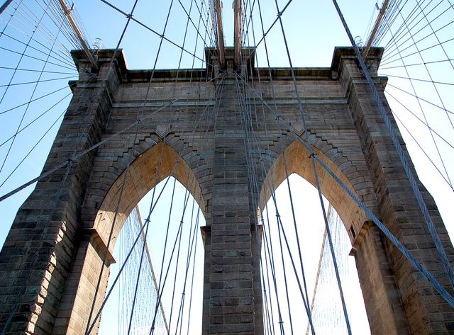 Showcasing the intricate architectural details and sturdy structure of the Brooklyn Bridge against a clear blue sky, this image is excellent for projects on civil engineering, iconic landmarks, urban planning, and travel. Suitable for use in educational materials, promotional campaigns, or architectural portfolios.