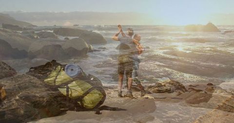 Mature couple dancing on rocky beach at sunset