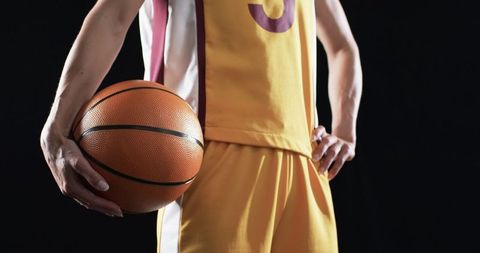 Female basketball player holding ball in sporty uniform