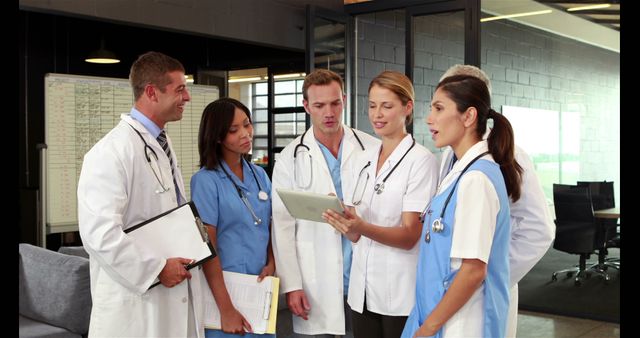 Medical professionals in a modern office reviewing patient records on a tablet. Team includes doctors and nurses collaborating and discussing healthcare strategies, highlighting teamwork and advanced technology in the medical field. Suitable for illustrating topics related to hospital administration, medical teamwork, patient care best practices, and health tech innovations.