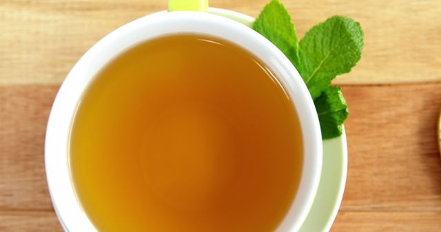A cup of tea with fresh mint leaves on a wooden surface, with copy space. Mint tea is popular for its refreshing flavor and potential digestive benefits.