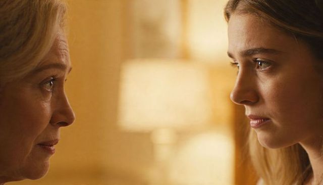 Facing off: two women exchanging tense looks with warm lamp bokeh, intimate home portrait