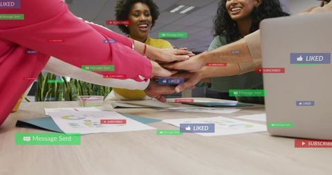 Diverse team joining hands in collaborative huddle over office desk with social media overlays